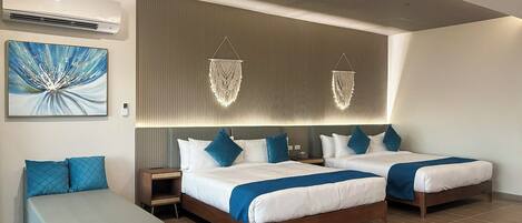 Una habitación de hotel moderna con dos camas, una zona de estar y un cuadro abstracto grande.