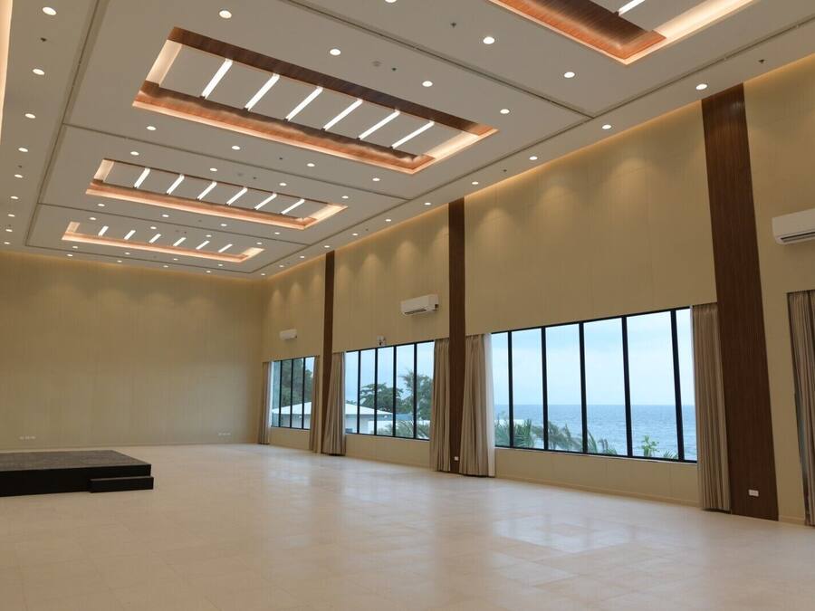 A spacious room with large windows, recessed lighting, and a view of the sea.