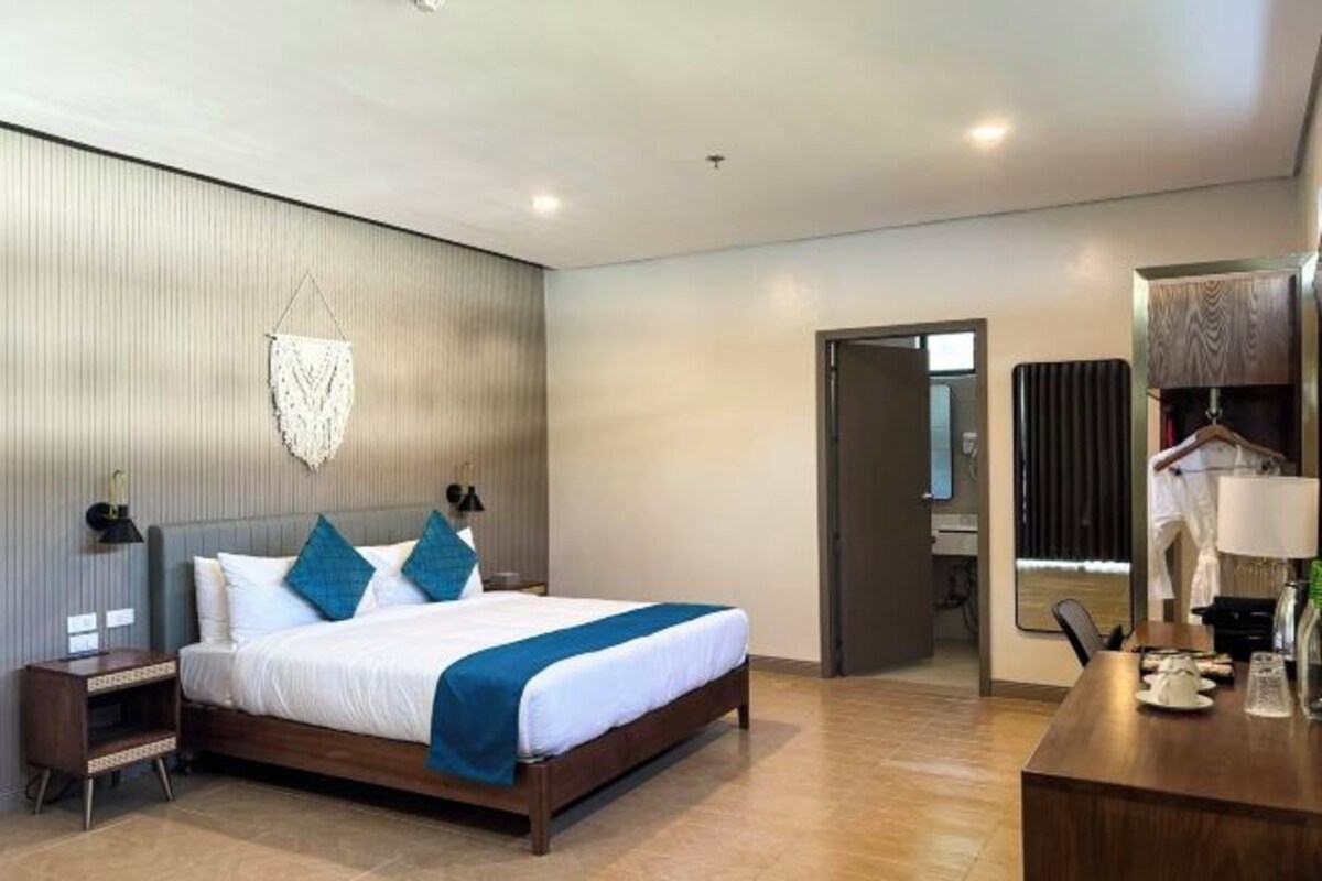 Une chambre d’hôtel moderne, dotée d’un grand lit, de tables de chevet, d’un bureau et d’une armoire.