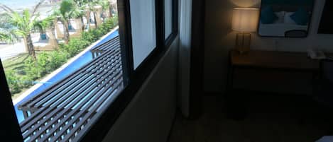 Una habitación con vista a la playa, un banco de madera, una lámpara y un cuadro en la pared.