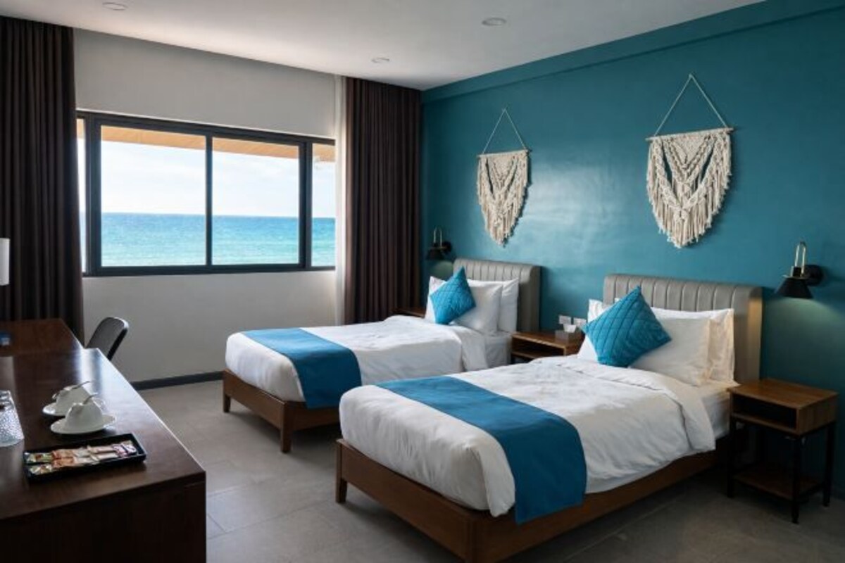 Une chambre d’hôtel avec deux lits, un bureau et une vue sur la mer.