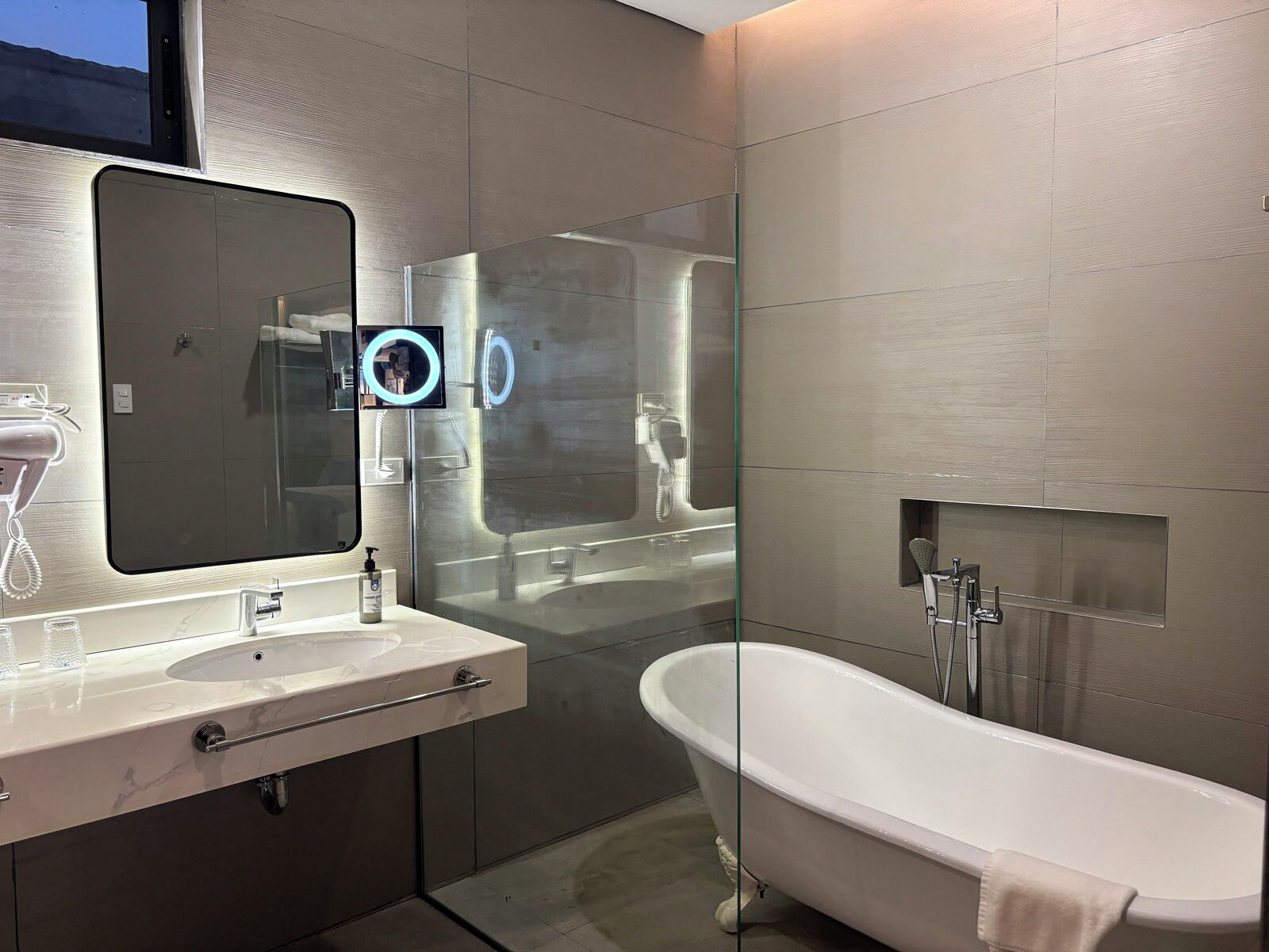 Un baño moderno con un espejo grande, tocador con lavamanos, bañera y zona de ducha.