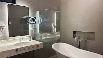Un baño moderno con un espejo grande, tocador con lavamanos, bañera y zona de ducha.