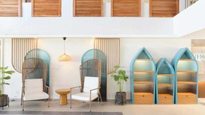 A modern lobby with wicker chairs, a round table, and blue shelving units. - Hudor Resort (Bauang)