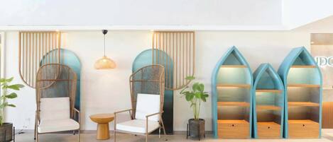 A modern lobby with wicker chairs, a round table, and blue shelving units.