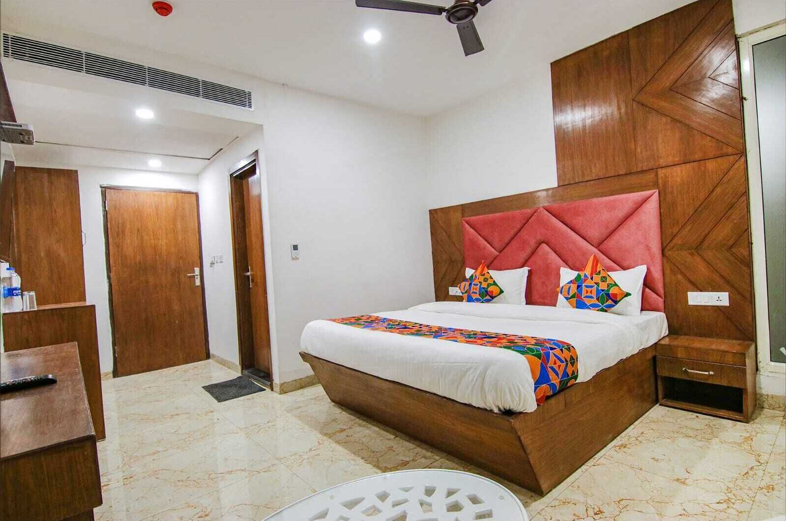Een hotelkamer met een groot bed, een houten hoofdeinde en een plafondventilator.
