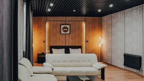 A modern living room with a sectional sofa, a coffee table, and a bed in the background.