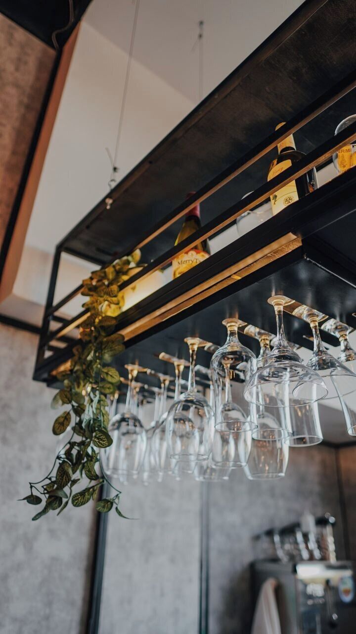 Un intérieur moderne avec un meuble à vin contenant de nombreux verres à vin et une plante suspendue.
