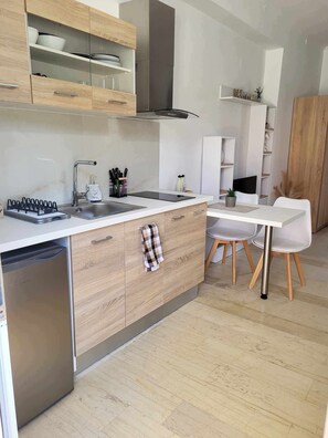 Eine moderne Küche mit eingebautem Geschirrspüler, einer Edelstahl-Spüle und einem Essbereich mit weißem Tisch und Stühlen.