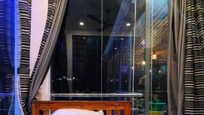 A hotel room with a large bed, a view of the city at night, and curtains on the windows.