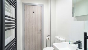 Un baño moderno con inodoro, lavamanos y toallero.