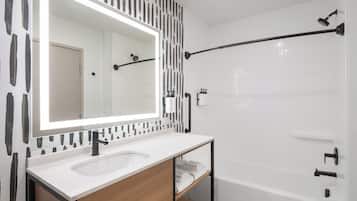 A modern bathroom with a white sink, mirror, and shower.