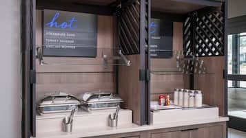 A breakfast buffet with labeled hot food options and condiments.