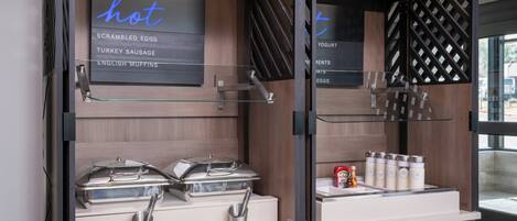 A breakfast buffet with labeled hot food options and condiments.