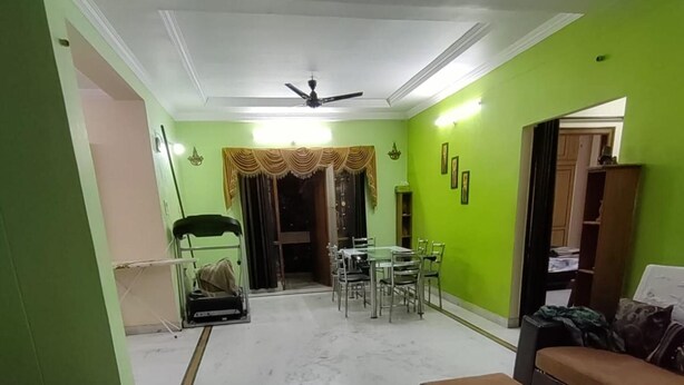 A dining area with a table and chairs, a ceiling fan, and a green wall. - Hyderabad Serenity Retreat - 3 Bdrm Apartment (Hyderabad)