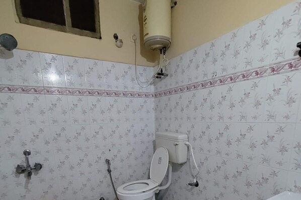 Un baño con inodoro, ducha y calentador de agua.