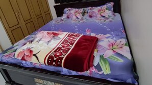 A bed with a floral bedspread and a red blanket. - Hyderabad Serenity Retreat - 3 Bdrm Apartment (Hyderabad)