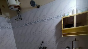 A bathroom with a shower, a toilet, and a sink. There is a towel rack and a soap dispenser on the wall. - Hyderabad Serenity Retreat - 3 Bdrm Apartment (Hyderabad)