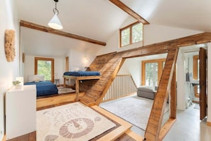 Ein Schlafzimmer im Loft-Stil mit einer Holztreppe, einem Stockbett und einem großen Fenster.