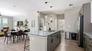 A modern kitchen with a central island, grey cabinets, and stainless steel appliances. - Charming, New Apt | Pool | Long Stays (Athens)
