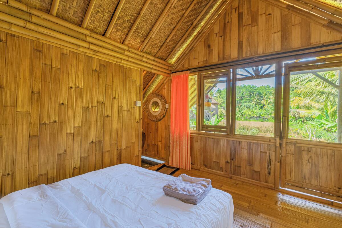 Una habitación de madera con una cama, un ventanal con vistas a follaje y una decoración circular en la pared.