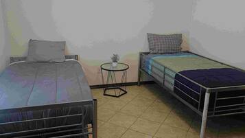 Una habitación con dos camas, una mesa redonda pequeña y una lámpara en el techo.