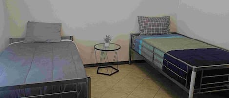 A room with two beds, a small round table, and a ceiling light.