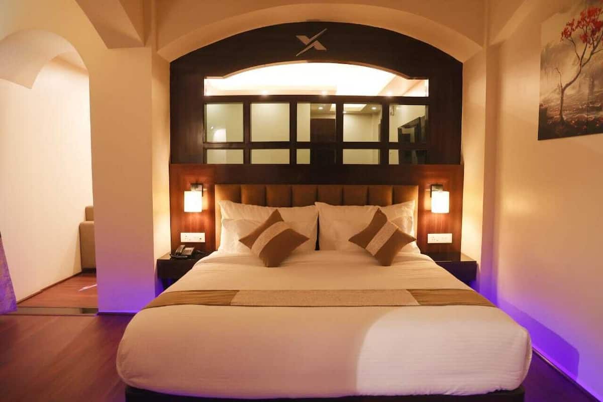A hotel room with a large bed, two bedside tables, and a modern headboard with a window above.
