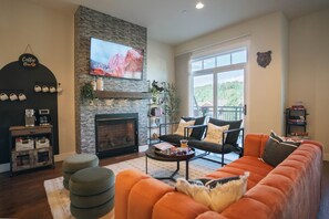 A living room with a fireplace, a sofa, a coffee table, and a television. - WinterPark*Ski*CoffeeBar*Pets+*CommunalHotTub (Winter Park)