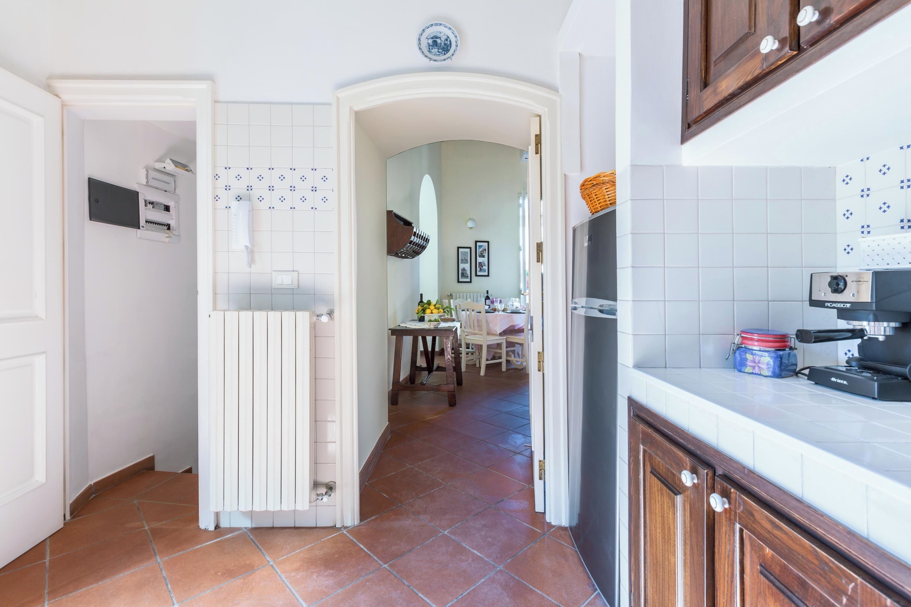 A kitchen with white cabinets, a tiled backsplash, and a dining area in the background.