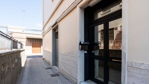 A narrow alleyway with a patterned tile floor leading to a building entrance with a black door and a mailbox. - Venus Apartment by Wonderful Italy (Bari)