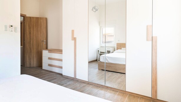 A modern bedroom with a large mirror, wooden wardrobe, and a bed. - Venus Apartment by Wonderful Italy (Bari)