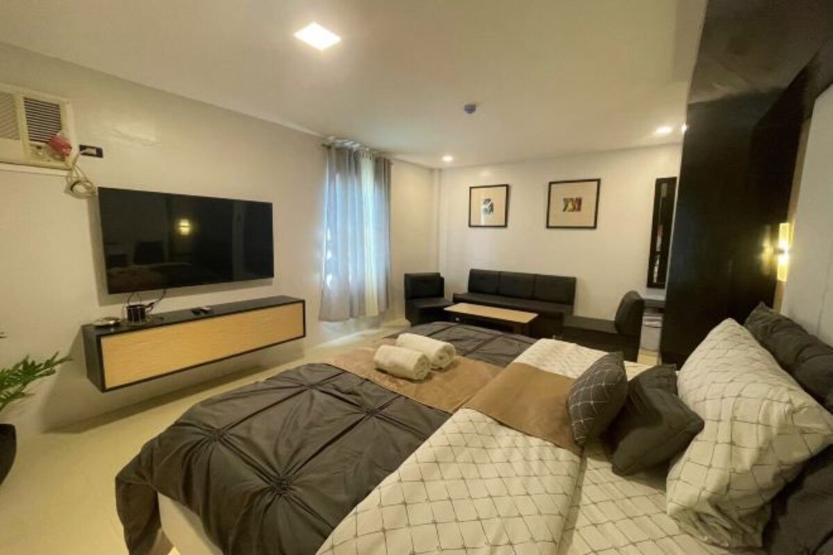 Une chambre d’hôtel moderne avec un grand lit, une télévision, un bureau et un canapé.