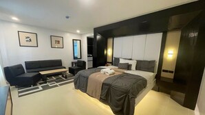 Una habitación de hotel moderna con una cama grande, un sofá, un escritorio y un televisor.
