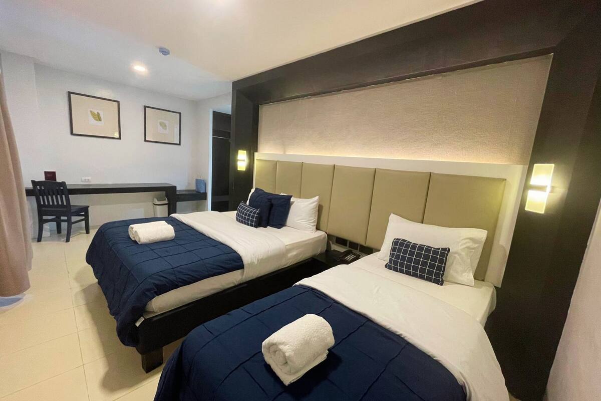 A hotel room with two beds, a desk, and a chair.