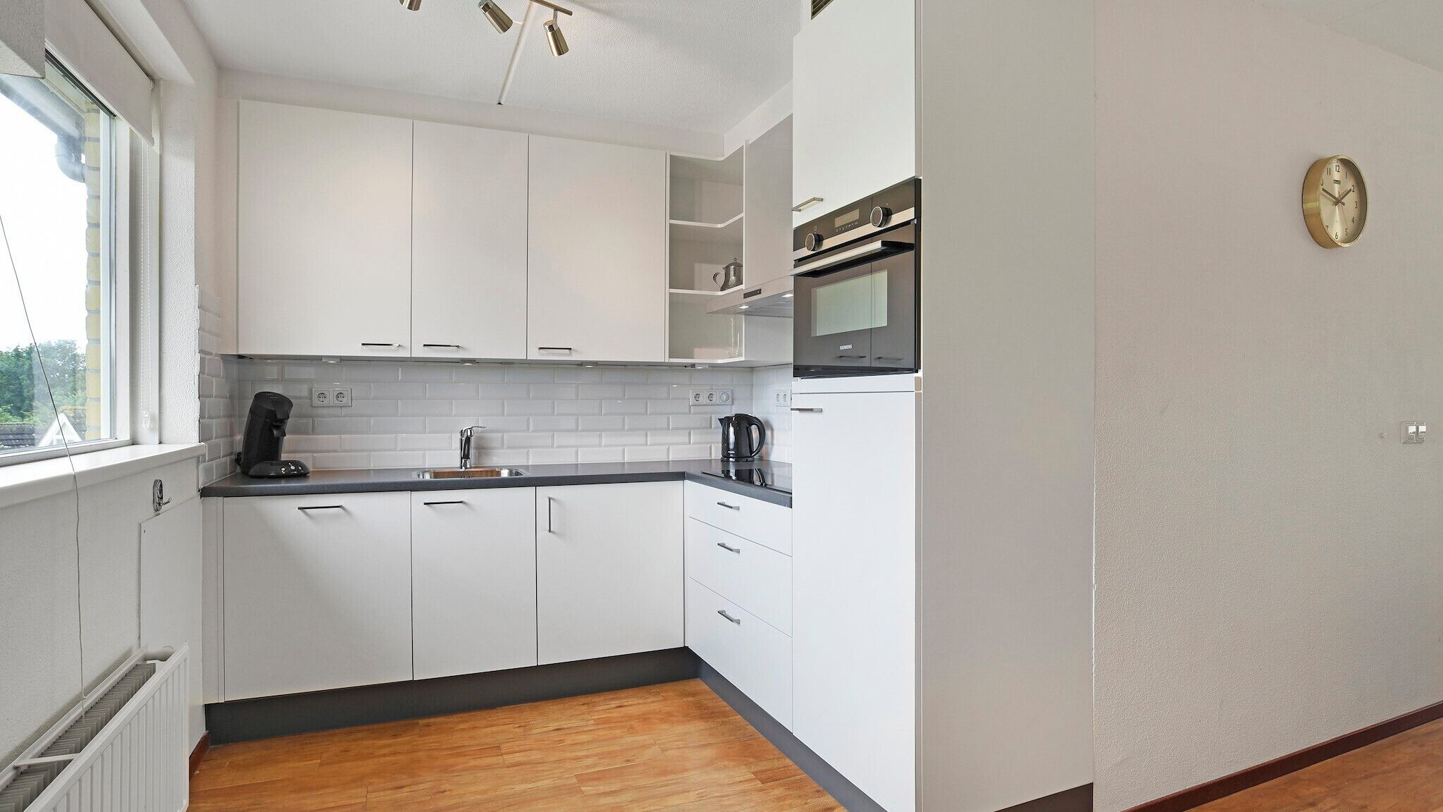 A modern kitchen with white cabinets, a black countertop, and a built-in oven.