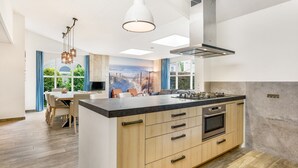 Eine moderne Küche mit einer großen Kochinsel, integriertem Backofen und Blick ins Freie.