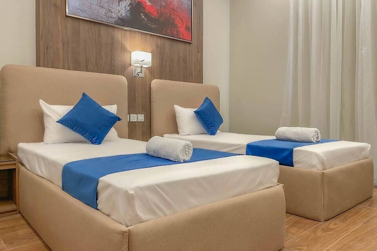 A hotel room with two beds, each with a blue and white bedspread, and a wooden headboard.