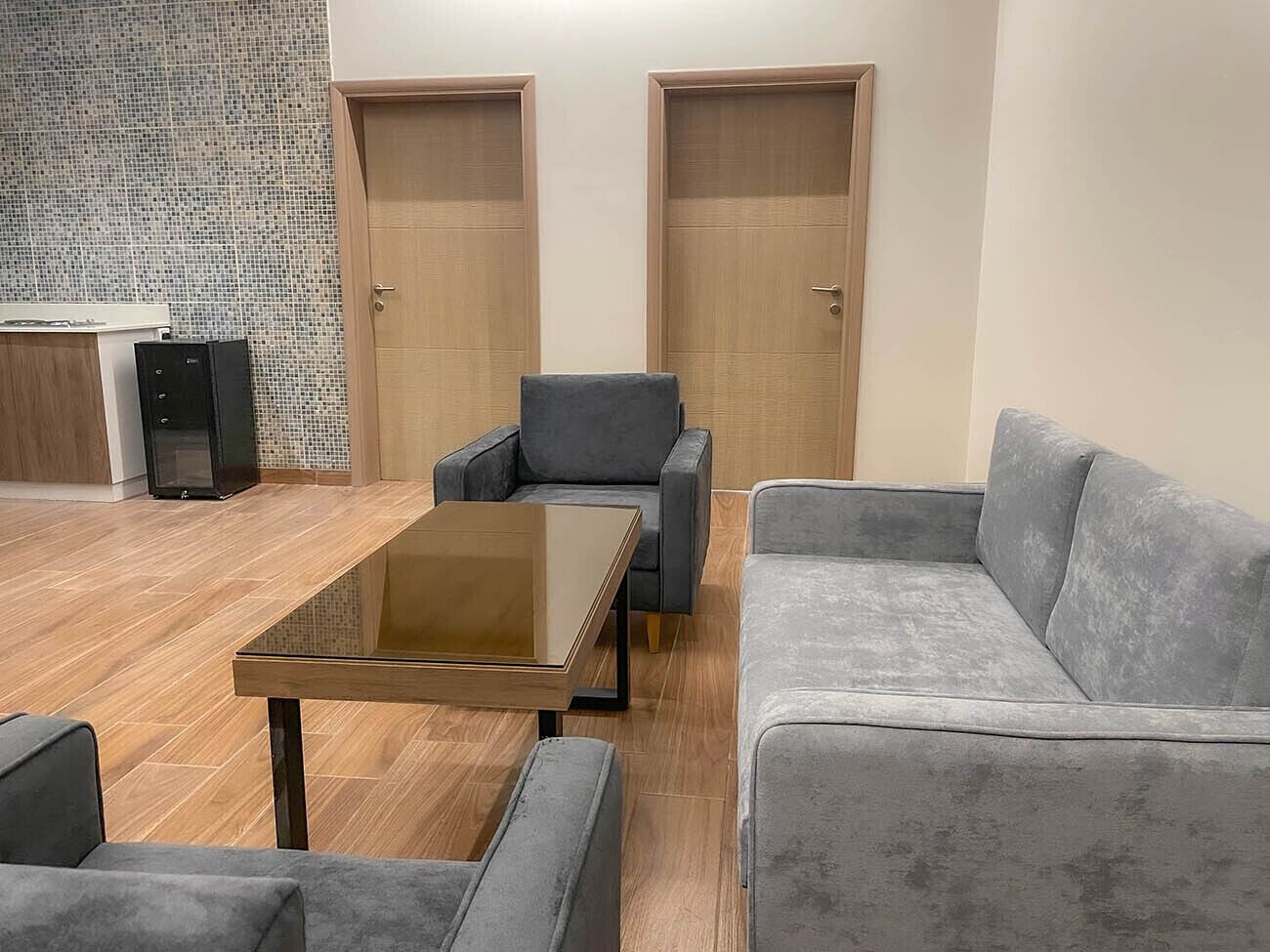 Ein moderner Konferenzraum mit Glastisch, grau gepolsterten Stühlen und einer grauen Couch.