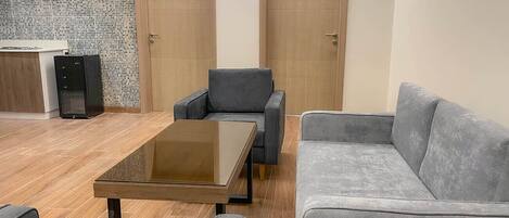 Ein moderner Konferenzraum mit Glastisch, grau gepolsterten Stühlen und einer grauen Couch.