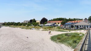 Una playa con orilla arenosa, algunas personas y edificios al fondo.