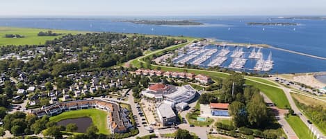 An aerial view of a coastal town with a marina, residential areas, and a large stadium.