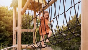 Un enfant qui escalade un pont de corde sur une structure de jeu en bois.