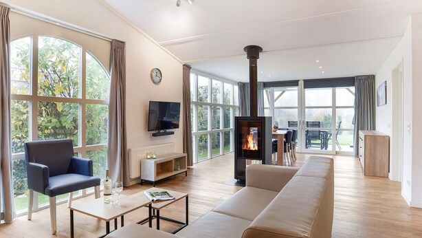 A spacious living room with a large sofa, a television, and a fireplace. - Bungalow for 6 persons with sauna (Brouwershaven)