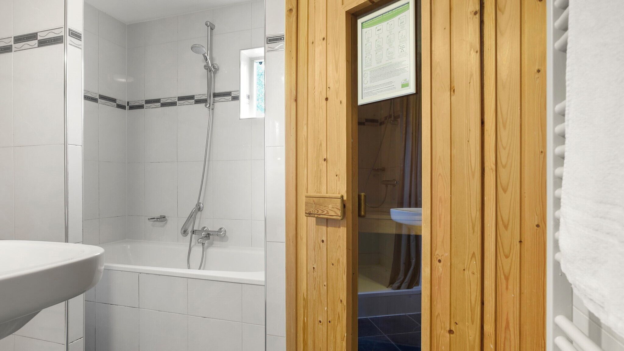A bathroom with a shower, a sink, and a wooden door.