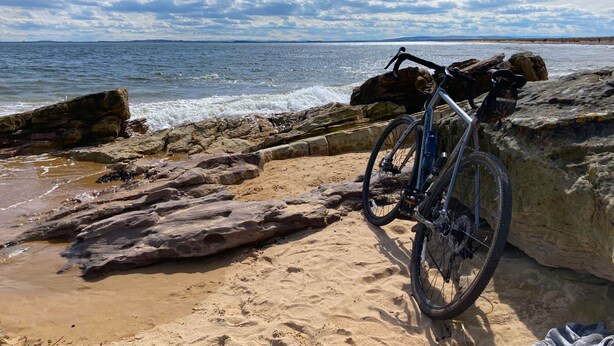 Ein Fahrrad steht auf einem felsigen Strand mit Blick auf das Meer.