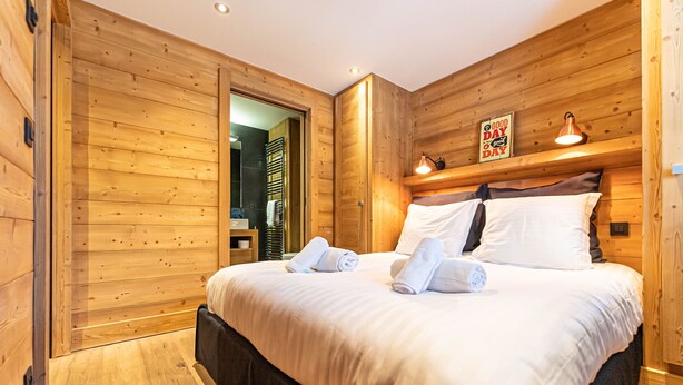 Ein Zimmer mit Holzwänden, einem Bett, Handtüchern und einem Schild mit der Aufschrift 'Good Day'.