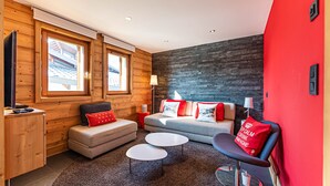 Ein modernes Wohnzimmer mit einer Couch, zwei Sesseln, einem Couchtisch und einem Fernseher.