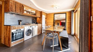 Eine moderne Küche mit Holzschränken, einem eingebauten Ofen und einem Essbereich mit Tisch und Stühlen.