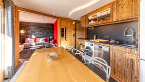 Eine moderne Küche mit Holzausstattung, einem integrierten Waschtrott und einem Essbereich mit Holztisch und Stühlen.